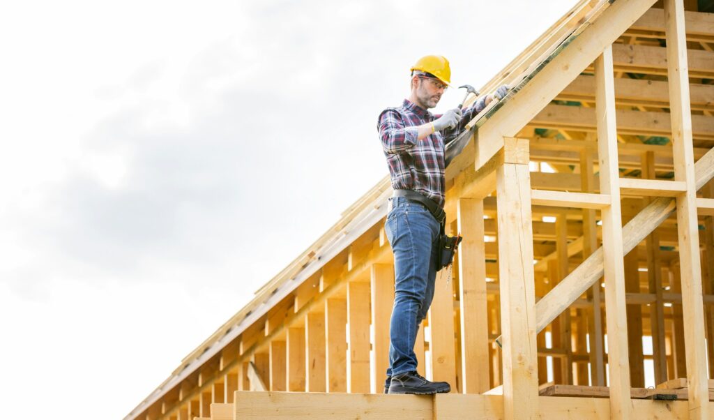 Roofer builder working on roof structure at construction site